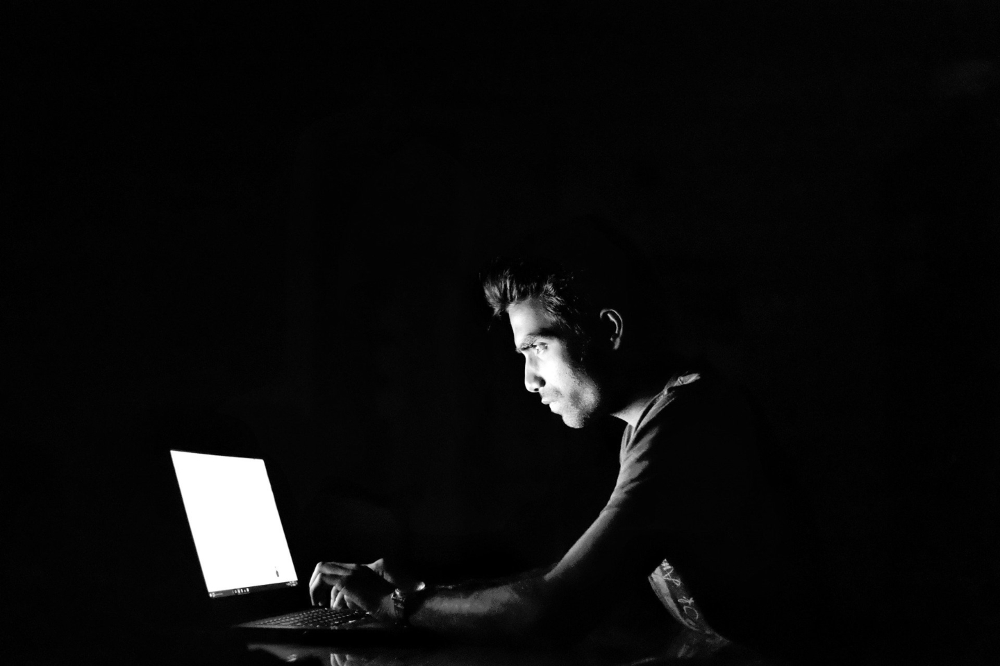 Chico sobre un fondo oscuro trabajando con su ordenador